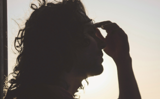 Eftertænksom kvinde i roligt rum – symbol på selvheling og indre refleksion ved kroniske symptomer